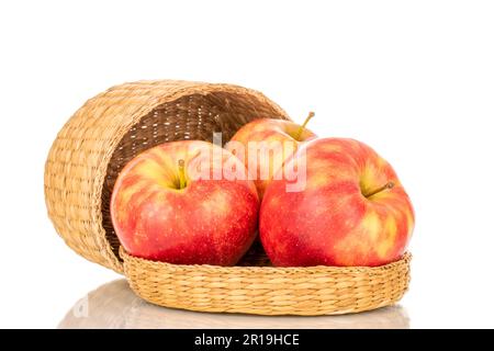 Three organic red apples in a straw basket, macro, isolated on white background. Stock Photo