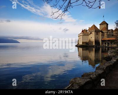 The ancient Chillon Castle on Lake Geneva against a blue sky Stock Photo