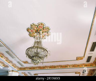 hall in an expensive hotel on vacation. a bulky, festive, huge chandelier made of glass and crystal is fixed on the white ceiling. meeting room decora Stock Photo