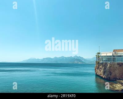 clear, blue water of the sea. a yacht with tourists floats on the water. next to the sea are high mountains. rest in a hot country by the water. swimm Stock Photo