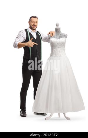 Tailor standing next to a bridal gown on a doll mannequin and pointing isolated on white background Stock Photo