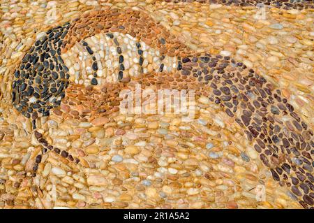 The texture of the stone wall, the road from small round and oval stones with abstracted lines of snake patterns with sandy seams of natural old yello Stock Photo