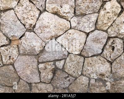 The texture of the wall is made of beautiful smooth, natural old, old, shuffled gray densely laid out without gaps, cobblestones, masonry with uneven Stock Photo