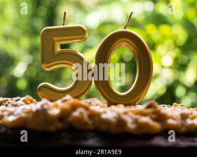 50th birthday golden clandles on a cake with green background Stock Photo
