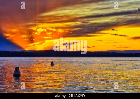 Floating buoys on Lake Macquarie at sunset - scenic landscape in Australia. Stock Photo