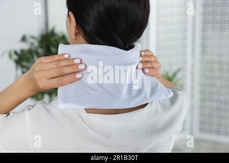 Woman using heating pad on neck at home, closeup Stock Photo