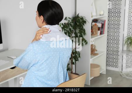 Woman using heating pad on neck at home Stock Photo