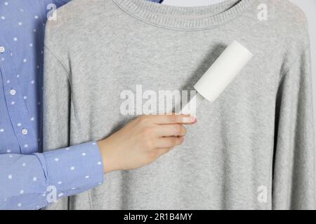 Woman cleaning clothes with lint roller, closeup Stock Photo