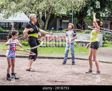 Adult woman playing with hula hoops  with three kids at a park in San José, Costa Rica. Stock Photo