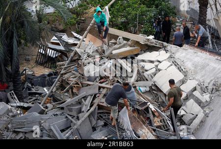 Palestinians inspect the rubble of a destroyed house of Islamic Jihad member Anas Al-Masri after Israeli air strikes late on 10 May in Beit Lahiya town, northern Gaza Strip. Palestinian militants in Gaza have fired rockets towards Israel, after the Israeli military carried out a series of air strikes on Islamic Jihad rocket launchers. Israel and Gaza militants traded heavy fire on May 11, the third day of the worst escalation of violence in months, which has killed 29 people in the blockaded Palestinian enclave and one in Israel. Stock Photo