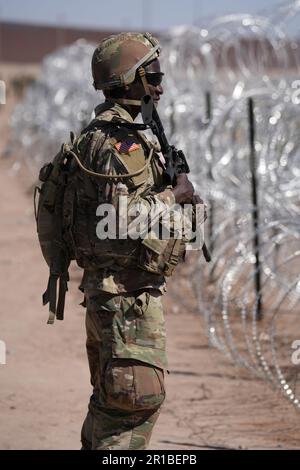 Members of the Operation Lone Star Task Force West and Texas Tactical Border Force block migrants from illegally entering Texas, May 11, 2023 near El Paso on the Rio Grande River. The units assumed blocking positions behind previously installed concertina wire in preparation for the expiration of Title 42. Stock Photo