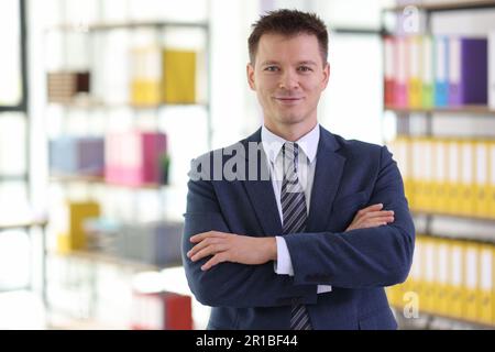 Successful businessman with crossed arms stands in office Stock Photo