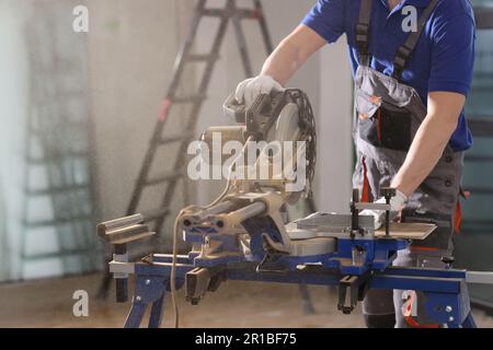 Worker in uniform cuts timber with sawing machine in shop Stock Photo