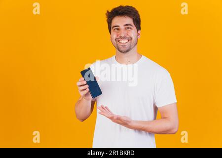 handsome man with cellphone in hands pointing with space for text Stock Photo