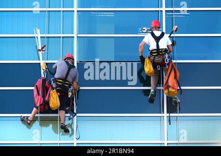 Two construction workers working at height on modern commercial skyscraper Stock Photo