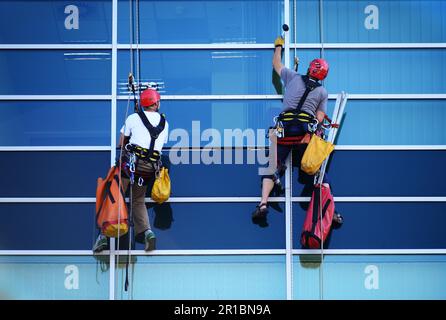 Two construction workers working at height on modern commercial skyscraper Stock Photo