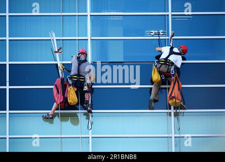Two construction workers working at height on modern commercial skyscraper Stock Photo