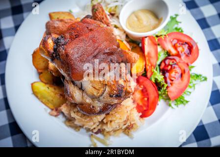 Schweinshaxe, pork hock baked with beer, bavarian cabbage and garlic, parsley steak potatoes. Stock Photo