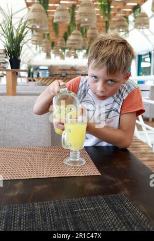 Boy filling glass with lemonade in restaurant Stock Photo