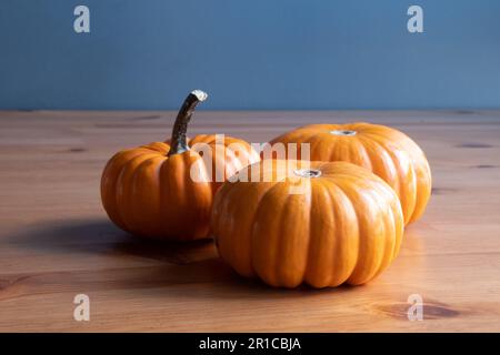 Small orange pumpkins on wooden table background. Front view of three small pumpkins Stock Photo