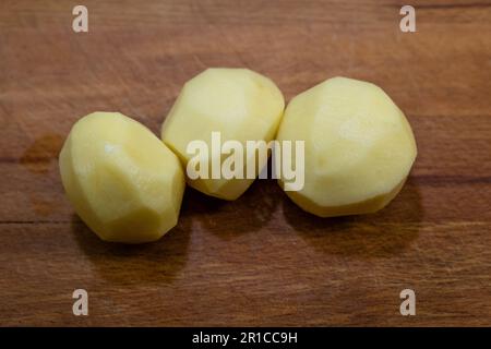 Raw peeled potatoes in bowl on dark wooden background. Stock Photo