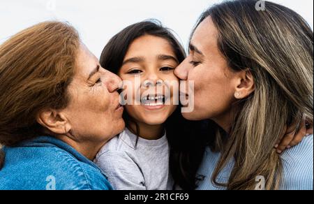 Happy Hispanic family enjoying time together - Child having fun with her mother and grandmother Stock Photo