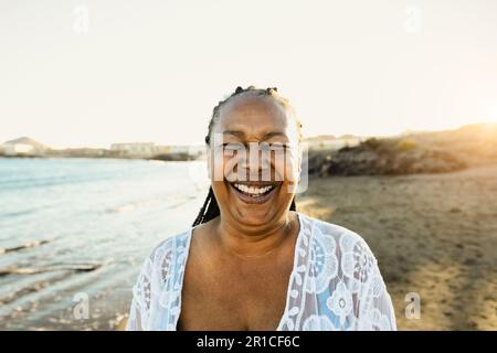 Happy African senior woman having fun smiling into the camera on the beach during summer vacation - Elderly people lifestyle concept Stock Photo