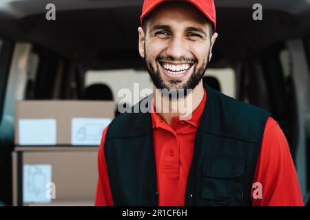 Young courier delivery man smiling into the camera while standing in front of his van transportation Stock Photo