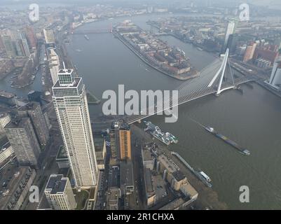 Marvel at the striking contrast between the iconic Erasmus bridge and towering skyscrapers in a stunning aerial drone photo of Rotterdam's skyline. Stock Photo