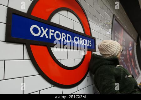 Oxford Circus Tube sign female sitting looking for approching train London UK Stock Photo