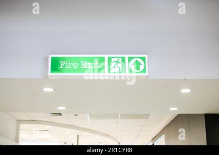 Source text White background fire exit sign White lettering is clearly positioned in a mall for customers to see in the event of an emergency or fire. Stock Photo