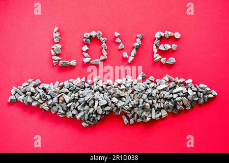 The "LOVE" letters from many small stones or pebbles are the concept of Valentine's Day or Love Day and are placed on a red background. Taking top vie Stock Photo