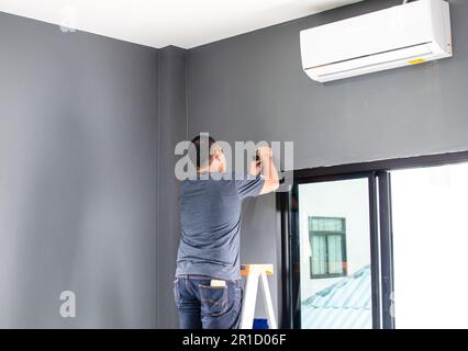 The technician is installing the air conditioner in the bedroom summer. A single man is working indoor in the building. Close up, Selective focus. Blu Stock Photo