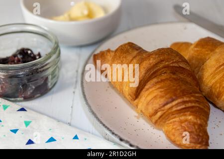 Two Croissants with Butter and Jam to the side with Knife on plate Stock Photo
