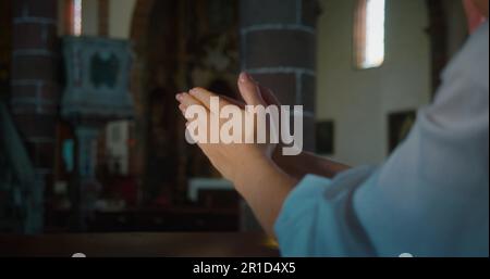Christian woman folded hands in prayer inside a church. Religious faith in power of Christ the Redeemer and Gods love. Stock Photo