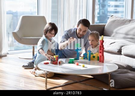 Excited cheerful dad enjoying leisure playtime with two little children Stock Photo