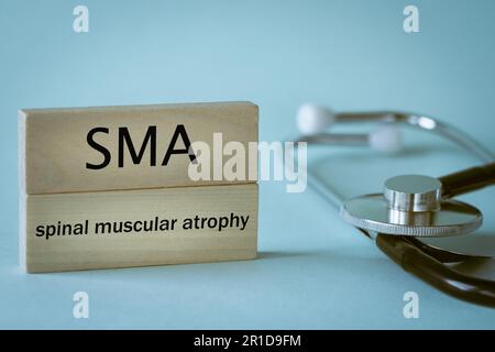 SMA Rare disease abbreviation Spinal Muscular Atrophy written on wooden blocks along with medical stethoscope, health concept, close up Stock Photo