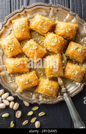 Baklava is a layered pastry dessert made of filo pastry, filled with chopped nuts and sweetened with syrup or honey closeup on the plate on the wooden Stock Photo