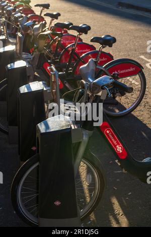 A row of Santander Cycles in a docking station, part of the TFL cycle hire scheme commonly called Boris Bikes Fashion Street, Spitalfields, London, UK Stock Photo