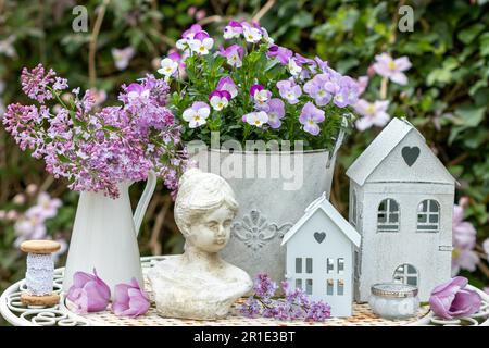 garden arrangemen with bouquet of lilac, viola flowers in pot, woman bust and vintage lanterns Stock Photo