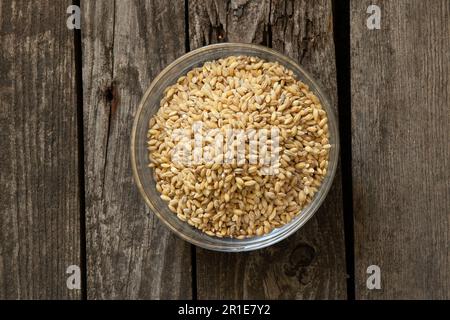 raw pearl barley in a plate stands on an table Stock Photo