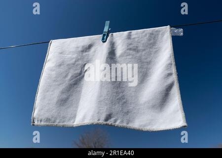 Clothes peg on a towel and washing line against a blue sky Stock Photo