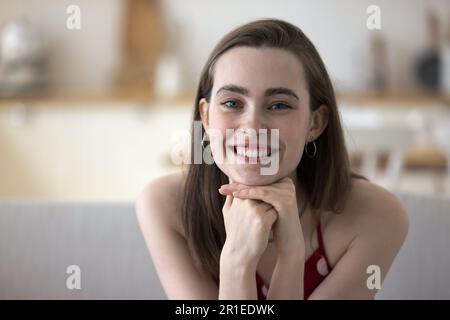 Happy pretty girl in sleeveless cloth leaning chin on hands Stock Photo