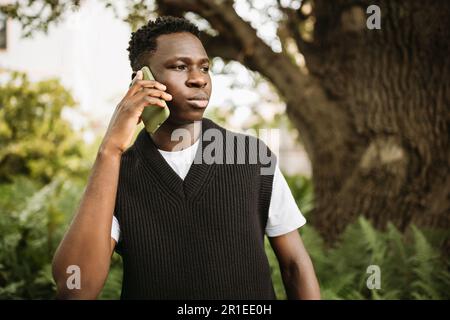 Young African man talking on phone shocked, stressed. Street portrait, copy space Stock Photo