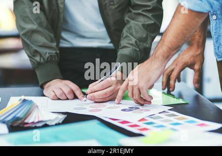 Covering the project from every angle. Closeup shot of two unrecognisable designers going through paperwork together in an office. Stock Photo