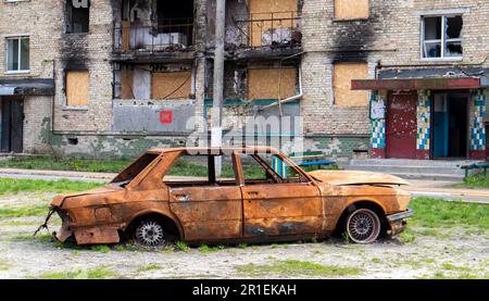 Consequences of the bombing in the city. The rocket blew up the house. A bombed-out apartment building and burnt-out cars after an airstrike. Holes in Stock Photo