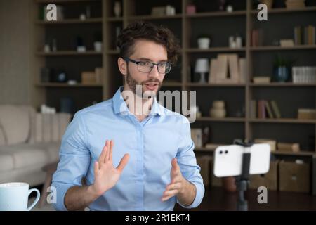 Handsome young business influencer in stylish eyeglasses streaming on Internet Stock Photo