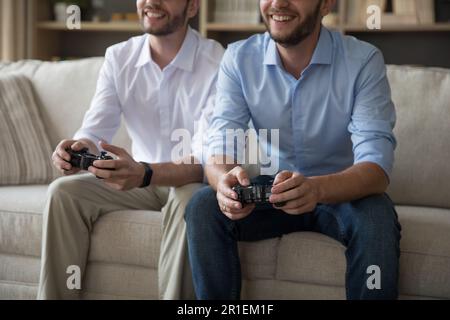 Cheerful positive adult similar twins playing video game Stock Photo