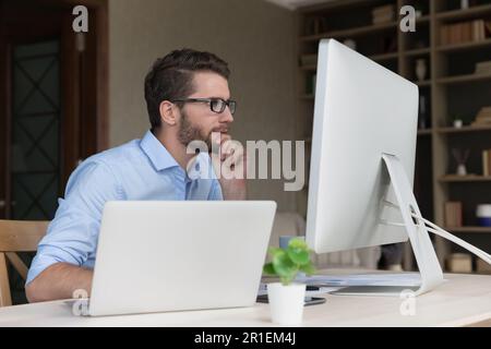 Serious busy young freelancer man working on online project Stock Photo