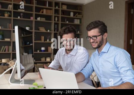 Happy confident twins in glasses working on family startup Stock Photo